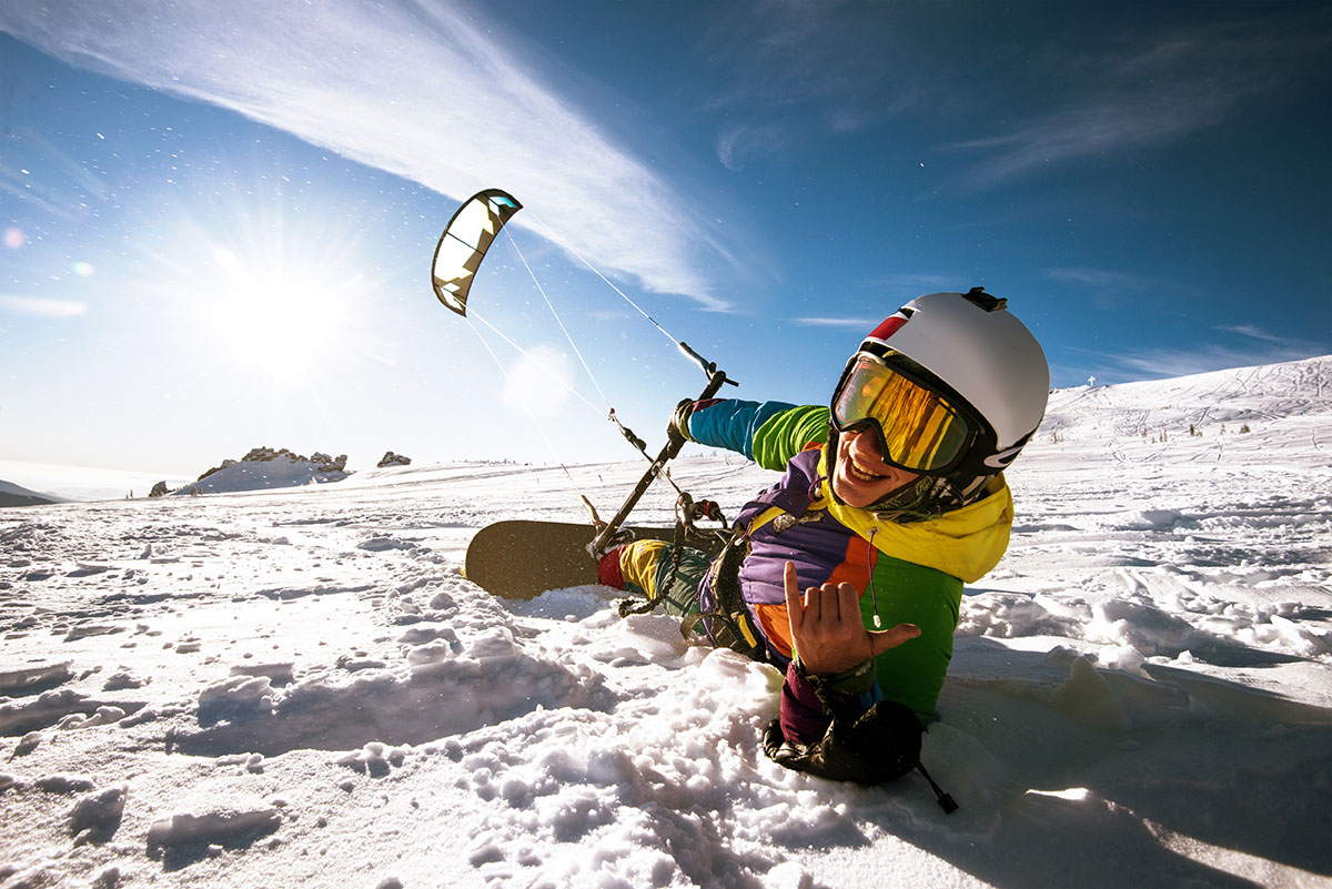 Happy snowboarder with kite lies in snowdrift. Sheregesh resort,