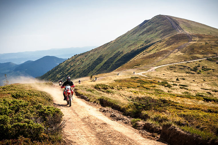 Enduro bikers crossing road in Carpathian mountains.